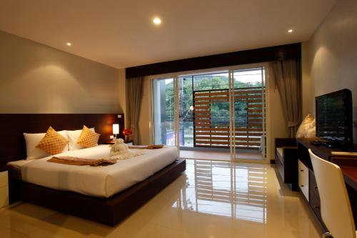 Nize Hotel - SHA Plus في فوكيت تاون: غرفة نوم بسرير كبير ونافذة كبيرة
