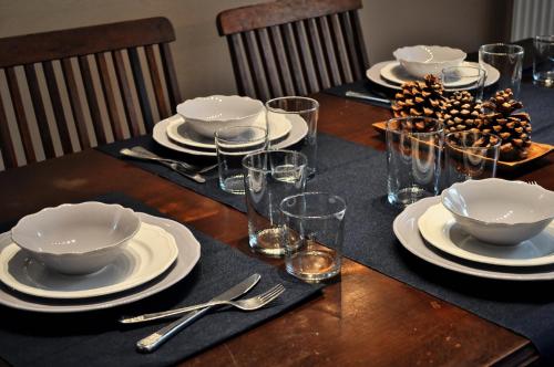 a table with plates and bowls and glasses on it at Chalet Coquelicot (Co-cli-co) relax in nature in Kalavrita
