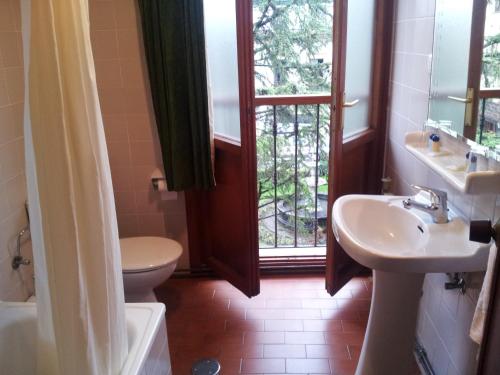 baño con lavabo y aseo y ventana en Hotel Restaurante El Manquin, en Villaviciosa