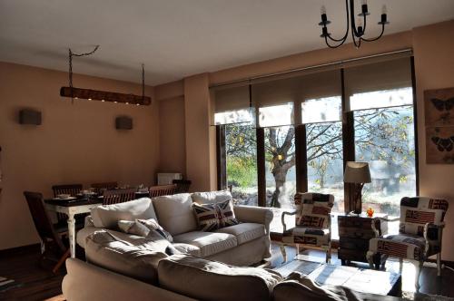 a living room with a couch and a table and windows at Chalet Coquelicot (Co-cli-co) relax in nature in Kalavrita