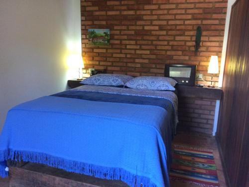 a bedroom with a blue bed with a brick wall at Flores de Cunha in Cunha