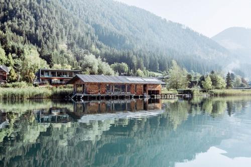 ein Gebäude auf einem Dock inmitten eines Sees in der Unterkunft Seehotel Enzian in Weissensee