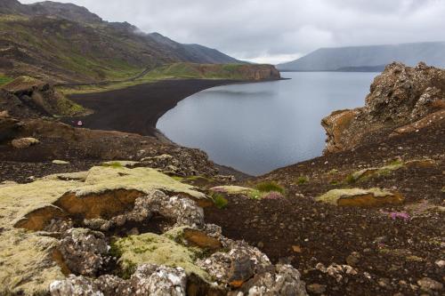 a lake on the side of a mountain with rocks at Northern Light Inn in Grindavík