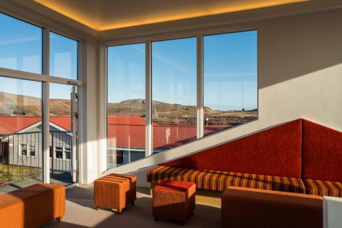 a room with a couch and chairs and large windows at Northern Light Inn in Grindavík
