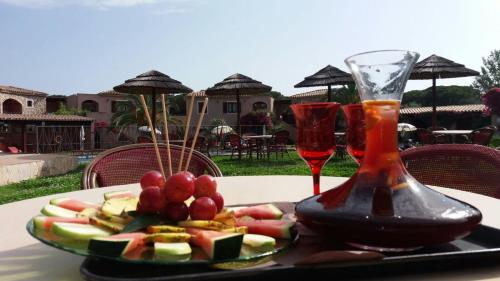 a plate of fruit on a table with wine glasses at Residence S'incantu in Villasimius