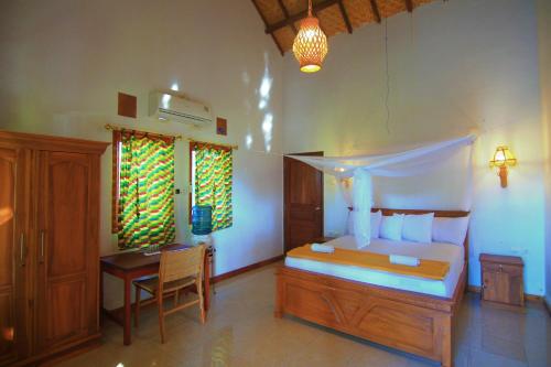 a bedroom with a bed and a desk and a bed and a table at Bidara Cottage in Labuhan Pandan