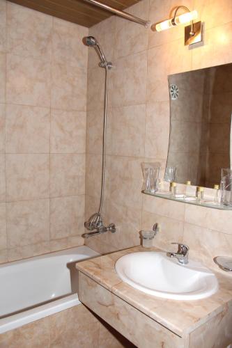 a bathroom with a sink and a tub and a mirror at Hotel Trakia in Pazardzhik