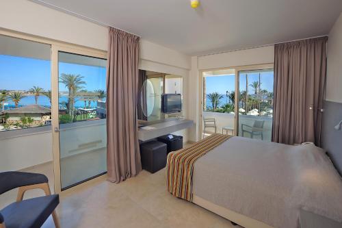 a bedroom with a bed and a view of the ocean at Nelia Beach Hotel & Spa in Ayia Napa