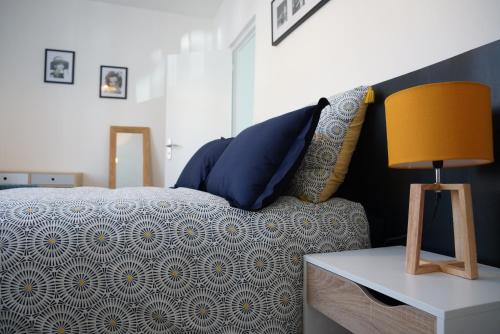 - un lit avec des oreillers bleus et une table avec une lampe dans l'établissement Mézières House, à Tourcoing