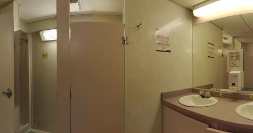 a bathroom with a shower and two sinks and a mirror at HI Castle Mountain - Hostel in Castle Junction