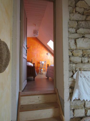 um corredor que leva a um quarto com uma parede de pedra em Chambres d'hôtes Les Arondelles em Virey-le-Grand