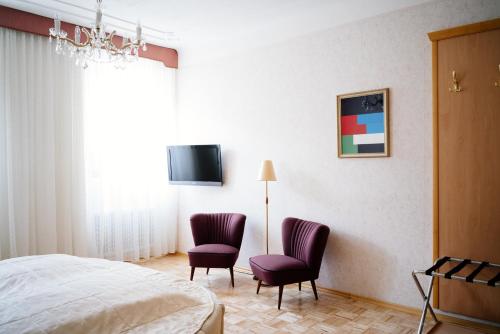 una camera con due sedie, un letto e una TV di Hotel Am Brillantengrund a Vienna