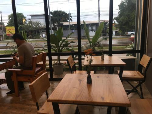 a man sitting at a table in a restaurant looking at his cell phone at Maerim Hostel in Chiang Mai