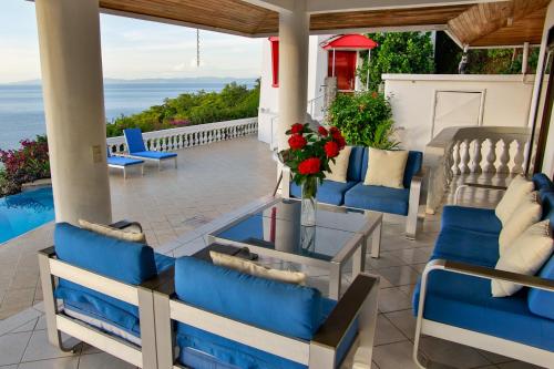 a patio with blue chairs and a table with flowers at The Lighthouse Ocotal in Coco