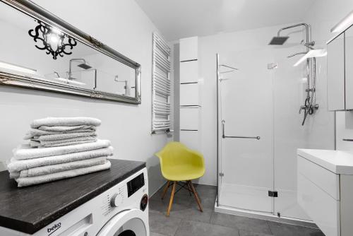 a white bathroom with a washing machine and a yellow chair at Apartament 555 Ogród w Centrum Apartamenty No.1 in Szczecin