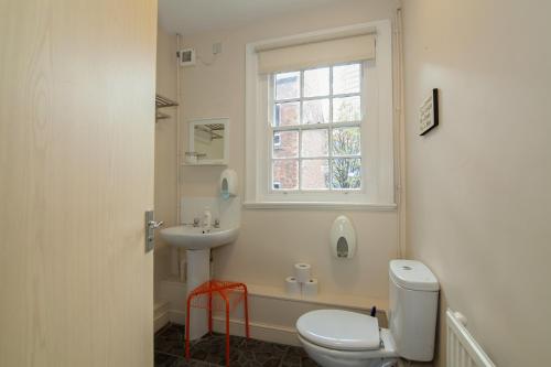 a bathroom with a toilet and a sink and a window at The Jollys in Bootle