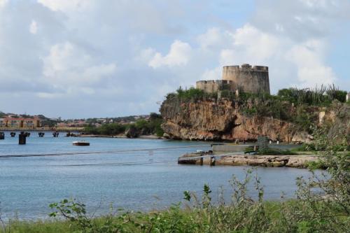a castle on a hill next to a body of water at Villa Unique in Willemstad