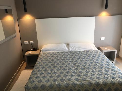 een slaapkamer met een groot bed met 2 nachtkastjes bij Hotel Rudy Cervia in Cervia