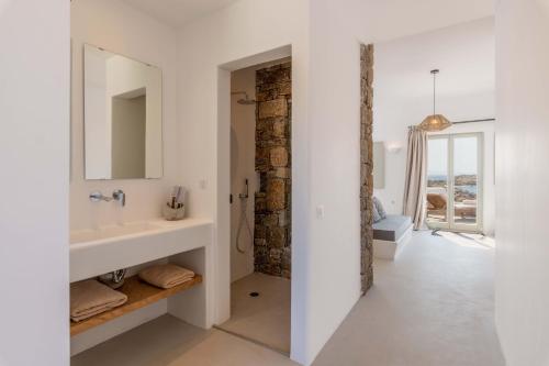 a white bathroom with a sink and a mirror at Trinity Mykonos - Beachfront Villa in Platis Yialos Mykonos