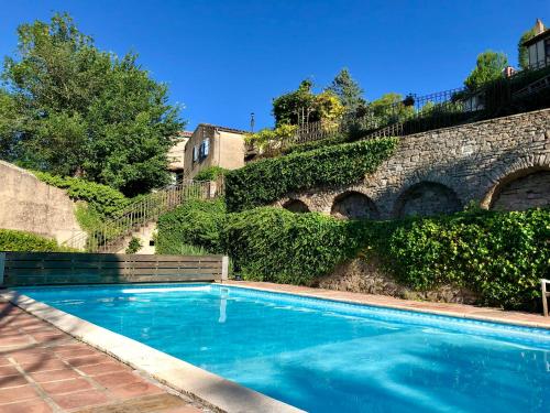 a swimming pool in front of a stone wall at Le Chevalier Noir in Cordes-sur-Ciel