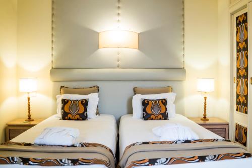 two beds in a hotel room with two lamps at INATEL Palace S.Pedro Do Sul in Termas de Sao Pedro do Sul