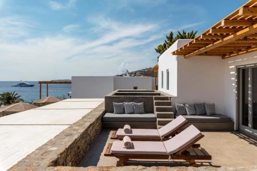 a patio with a couch and chairs on a house at Trinity Mykonos - Beachfront Villa in Platis Yialos Mykonos