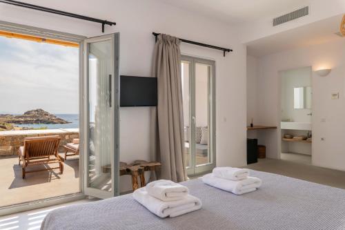 a bedroom with a bed and a view of the ocean at Trinity Mykonos - Beachfront Villa in Platis Yialos Mykonos