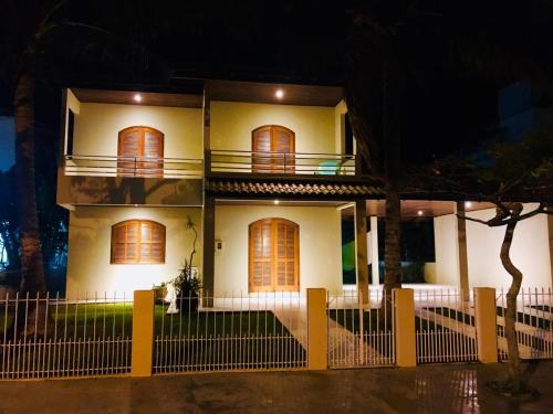 ein weißes Haus mit einem Zaun davor in der Unterkunft Casa ampla próxima da praia - Praia de Palmas in Governador Celso Ramos