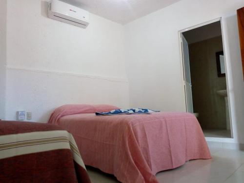 a bedroom with two beds with a pink blanket at Pie de Playa la Ropa in Zihuatanejo
