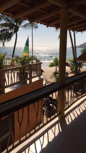 a balcony with a view of a beach with a sailboat at Pie de Playa la Ropa in Zihuatanejo