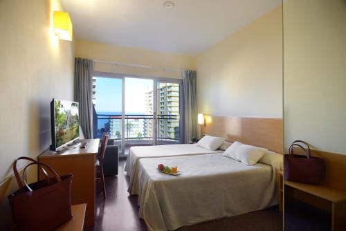 a hotel room with a bed and a television at Hotel Miramar Playa in Playa de Miramar