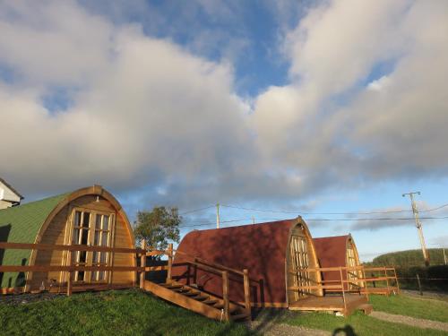 a group of three wooden buildings in the grass at Shannon Estuary Glamping in Effernan