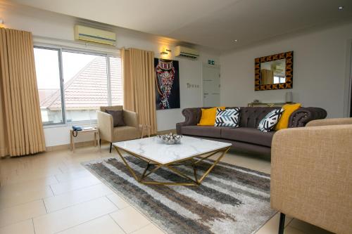 een woonkamer met een bank en een salontafel bij The Avery Apartments, Dzorwulu in Accra