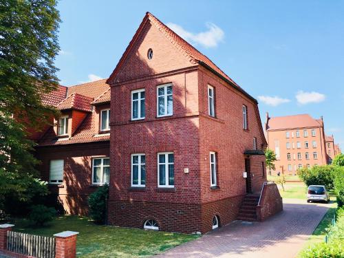 a red brick house with white windows on a street at Pension Sellent in Stendal