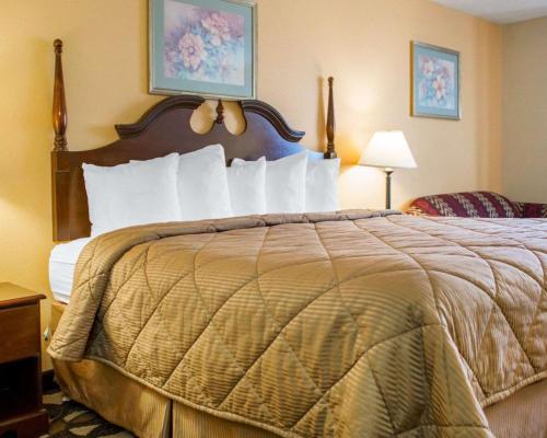 a hotel room with a bed with white pillows at Quality Inn Broken Arrow - Tulsa in Broken Arrow