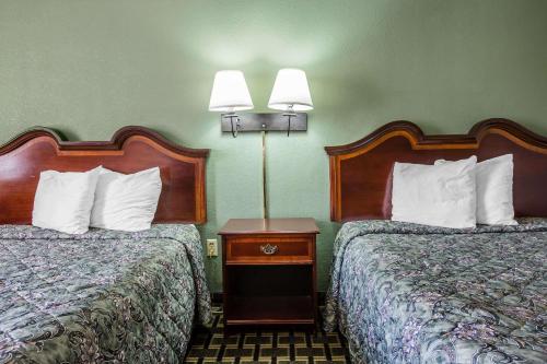 two beds in a hotel room with two lamps at Rodeway Inn in Laurens