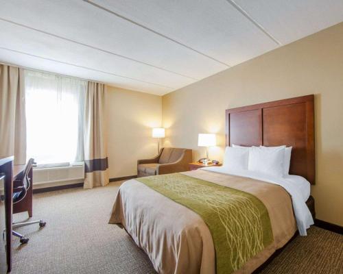 a hotel room with a large bed and a chair at Comfort Inn at Royal Blue in Pioneer
