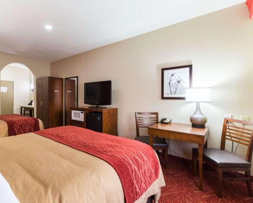 a hotel room with a bed and a desk and a tv at Econo Lodge Inn & Suites East Houston I-10 in Houston