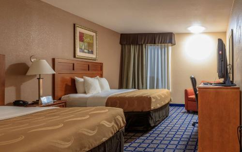 a hotel room with two beds and a flat screen tv at Quality Inn Forest Hill - Fort Worth South in Forest Hill