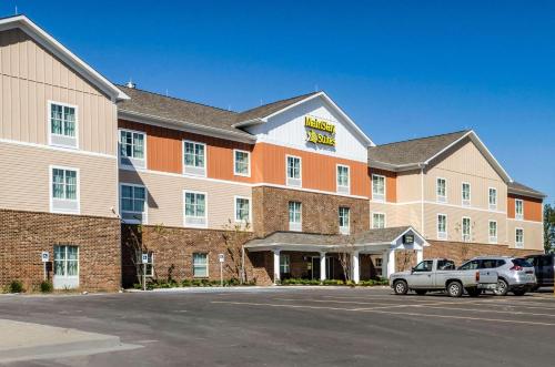 a hotel with two cars parked in a parking lot at MainStay Suites Hackberry Sportsman's Lodge in Hackberry