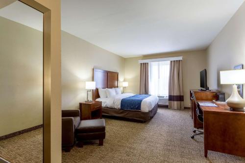 a hotel room with a bed and a desk and a mirror at Comfort Inn & Suites Airport in Baton Rouge