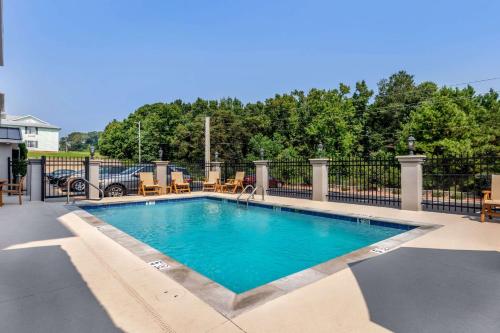 a swimming pool with blue water in front of a fence at Sleep Inn & Suites Millbrook - Prattville in Millbrook