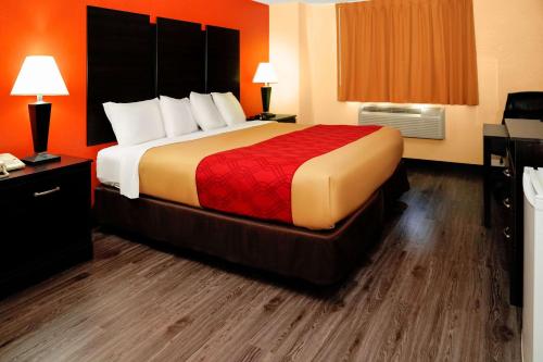 a large bed in a hotel room with orange walls at Econo Lodge Rome in Rome