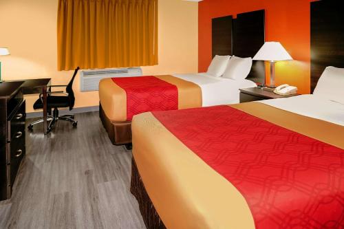 a hotel room with two beds and a desk at Econo Lodge Rome in Rome