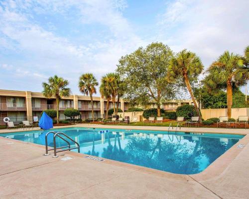a swimming pool at a resort with palm trees at Clarion Inn & Suites Dothan South in Dothan