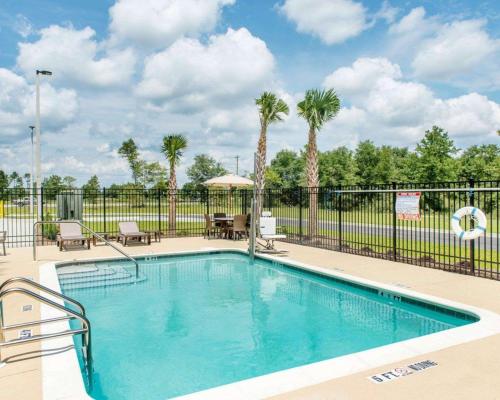 einen Pool mit einem Zaun und Palmen in der Unterkunft Sleep Inn & Suites Defuniak Springs in Mossy Head