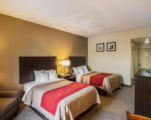una habitación de hotel con 2 camas y una silla en Quality Inn Hayti North, en Hayti