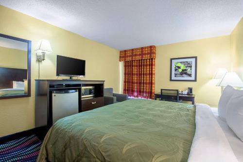 a hotel room with a bed and a flat screen tv at Quality Inn Holly Springs South in Holly Springs