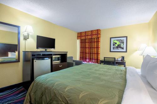 Una habitación de hotel con una cama y un televisor de pantalla plana. en Quality Inn Holly Springs South, en Holly Springs