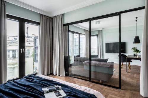 ソポトにあるMontevideo Centrum 10 by Grand Apartmentsのベッドルーム1室(ガラスの引き戸付)、リビングルームが備わります。